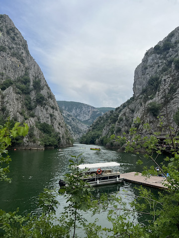 A canyon with a river flowing through it. There is a boat in the middle of the river.